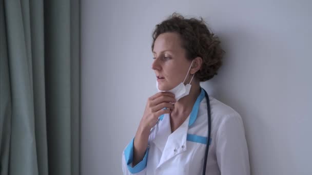 Ärztin Lehnt Aus Müdigkeit Wand Nimmt Maske Und Versteckt Emotionen — Stockvideo