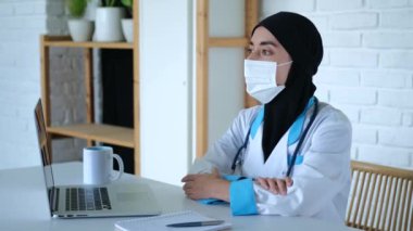 Müslüman kadın doktor dizüstü bilgisayarın başında otururken mesafeye bakar. Yakınlarda konsantre iş için gereken her şey var. Kahve, not defteri ve dizüstü bilgisayar. Doktor teşhisi bilgisayara yazmayı düşünüyor.