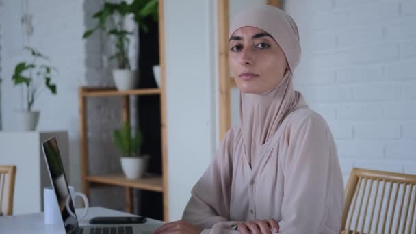 ラップトップやノートブックに囲まれた真剣な外観を持つイスラムのビジネスマン 東部の女性は 深刻なリーダーシップの地位を占める機会があることを誇りに思っています 世界の平等についての真剣な話題 — ストック動画