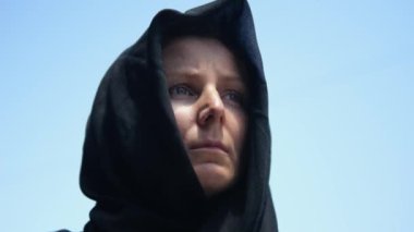 Yakın plan dul bir kadın, yorgun bir yüzü ve mavi gökyüzüne karşı üzüntüden kırışıklıkları var. Trajik olaylara rağmen, yorgun kadın umut doludur. Sivillerin sonu gelmeyen savaş ve trajedilerden bıktığı kavramı.