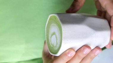 Elinde yeşil canlandırıcı kibrit içeceği olan kil bardak var. Popüler sağlıklı eşleşmelerle dolu el yapımı yemekler. Sağlıklı eşleşme ve çevre dostu sofra takımı arasındaki uyum kavramı.