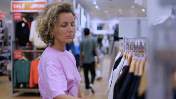 Giyim Mağazasındaki Kadın Bluzlara Bakıyor Alışveriş Sürecinden Zevk Alıyor Alışveriş — Stok video