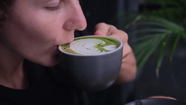 漂亮的女人喝了一大杯时髦的马沙绿茶 在嬉皮士咖啡店里享受着令人惊叹的拿铁艺术 有机绿色的桅杆充满了疗愈力 理想的早茶概念与绿咖啡 — 图库视频影像