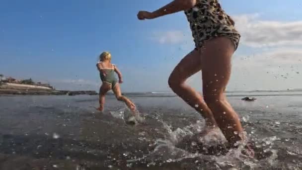 아이들은 햇볕이 해변을 달리며 튀깁니다 슬로우 모션에서는 효과적으로 태양에 반짝입니다 — 비디오