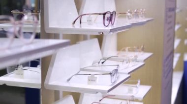 Mağazadaki raflarda zarif bardaklar var. Gözlük tasarımı ve mağazanın hoş atmosferi seçim sürecini kolaylaştıracak. Optik mağazasında vizyon için güzel gözlük seçimi kavramı