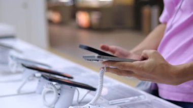Yakın plan akıllı müşteri cep telefonu dükkanında akıllı telefonlar arasında seçim yapıyor. Kadının mağazadan telefon alırken bilinçli bir karar vermesi gerekir. Modern aygıtlar deposunda çeşitli seçimler.