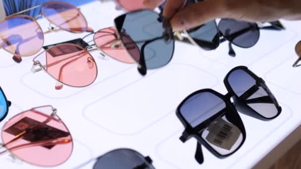 Närbild Kvinnor Hand Solglasögon Från Skyltfönster Fönstret Visar Dussintals Modeller — Stockvideo