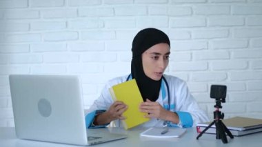 Müslüman doktor kitabı görüntülü sohbet ile yayınlanıyor. Orta ölçekli görüntüler: tesettür ve medikal elbise içindeki Müslüman kadın doktorlarla iletişim kurmak için görüntülü sohbet formatını kullanma kavramı ile bir şeyler anlatıyor