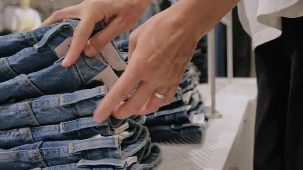 Kvinnan Väljer Jeans Klädaffären Närbild Kvinnor Händer Sortera Igenom Stack — Stockvideo