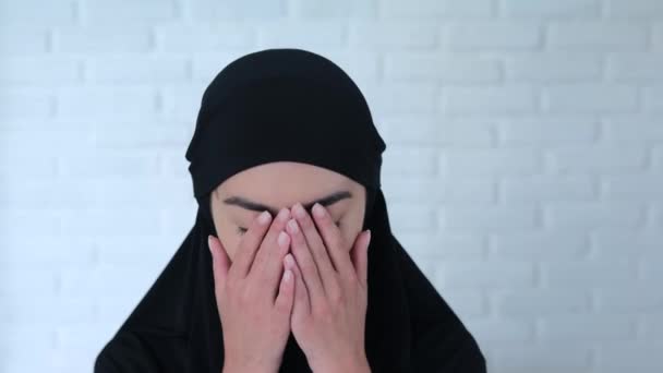 黒いヒジャーブのムスリム女性は手で顔を覆いました クローズアップショット 黒いヒジャーブのムスリム女性は頭を下げ 目を閉じて 手のひらで顔を覆いました コンセプト 手のひらで顔を覆うムスリム女性 — ストック動画