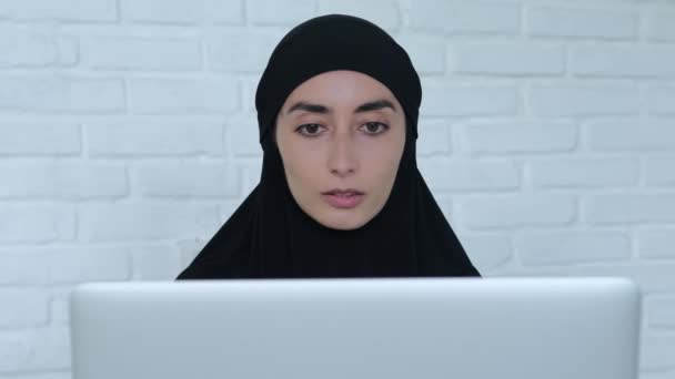穿着黑色头巾的穆斯林妇女在笔记本电脑上保持着紧密的联系 认真负责的穆斯林女士办公室职员坐在办公桌前 用笔记本电脑发短信 查看商业信函 网上对应的概念 — 图库视频影像