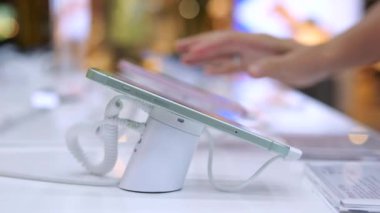 Alıcı vitrindeki yeni cep telefonu fonksiyonlarını inceliyor. Geniş ekran ve şık tasarımı olan telefon, cihaz kullanıcıları için telefon satın almanın büyük bir yatırım olacağını gösteriyor.