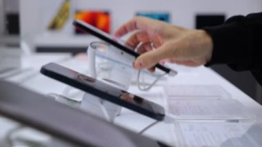 Dükkanda telefonları test ediyorum. Yakın plan: telefonu kaldır ve elektronik mağazasında kontrol et. Konsept: mağazadaki telefon işlevlerine aşina olun ve size uygun olanı seçin