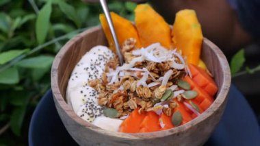 Smoothie kasesinde vejetaryen yemeği yakın plan. Üst manzara: papaya parçaları ve chia tohumları, granola ve hindistan cevizi taneleri smoothie kasesinde. Smoothie kasesinde lezzetli ve tatmin edici vejetaryen yemeği kavramı
