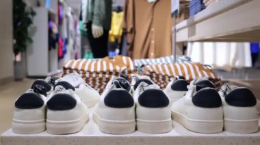 Butikte ayakkabı ve tişörtler masanın üzerinde. Seçici Odak: Butikte masanın üzerinde birkaç çift ayakkabı ve tişört. Arkasında manken var. Konsept: Butikte uygun kıyafet ve ayakkabı alımı