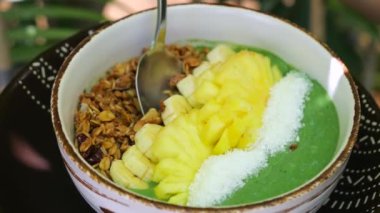 Smoothie kasesinde doyurucu bir kahvaltı. Yakın plan: muz ve ananas parçaları, tahıl gevreği ve bol miktarda avokado püresi - bu kasede doyurucu bir kahvaltı. Sağlıklı yemek, sağlıklı kahvaltıyla başlar.