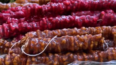 Doğu pazarındaki tezgah. Lezzetli kilise çantasıyla dolu. Yoğun üzüm şurubuyla kaplanmış fındıklardan yapılmış renkli kilise sosisleri güneşte parlıyor. Chuchkhella lezzetli ve sağlıklı lezzet