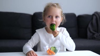 Çocuk mutlu bir şekilde sağlıklı brokoli ve diğer sebzeleri yiyor. Tabak, çocukların iştahla yediği çeşitli sağlıklı sebzelerle doludur. Kız sağlıklı yiyeceklerden anlıyor ve zevk alıyor..
