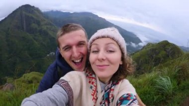 Sevgi dolu çiftler dağlarda selfie çekerek gezerler. Parlak olumlu duygular yayarlar. Mutluluğun tadını çıkarırlar. Birbirine aşık çiftler dağları keşfeder mutlu selfie çekerek yolculuklarının mutluluğunu yakalarlar.