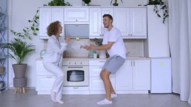 Genç çift mutfaklarında neşeyle dans eder. Olumlu duygular. İlişkilerde dans etmeye bayılırlar. Kafkasyalı karı koca modern mutfakta dans ediyor olumlu duygular iyi ilişkileri seviyor