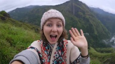 Turist, Asya 'daki nefes kesici dağlara karşı selfie çekiyor. Kadın selfie çekerken kameraya el sallıyor. Unutulmaz selfie 'ler için nefes kesici manzaralar dağlarda yeşil bir yolculukta..