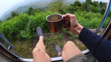 Sri Lanka 'nın güzel dağlık bölgelerine açılan kapılarıyla trendeki Pov heyecanlı bir turist. Seyahat ederken, insanlar çarpıcı manzaranın tadını çıkararak trenden sallanıyordu. Eldeki kupada gezintiye rahatlık katıyor..
