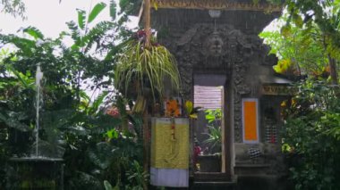 Yağmur yağarken geleneksel Bali tapınağı. Tapınak, elementlere rağmen görkemli bir şekilde duruyor. Su iskeleti mimari tapınağını dereler, mistik bir atmosfer yaratır. Yağmur antika ve dayanıklılığı vurgular.