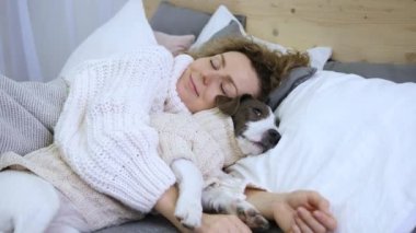 Sahibi ve sadık köpeği geniş bir yatakta uyur. İkisi de rahat kazaklar giyiyor. Sahibi evcil hayvanı nazikçe kucaklıyor, dokunaklı bir sahne yaratıyor. Sahibi ve köpeği arasındaki bağ güçlüdür. Sıcak kollarda huzurlu bir uyku..