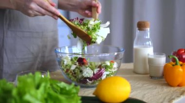 Yakın plan kadın mutfakta sebze salatası karıştırıyor. Becerikli hareketler ev yemeklerinde ustalaştığını gösteriyor. Atış, sağlıklı ve lezzetli salataların üretildiği atmosfer rahat mutfağı taşır. Taze yemek yapıyorum..