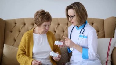 Doktor yaşlı hastaya reçete yazıyor ve aldığı ilaçları açıklıyor. Doktor hastaya reçeteli ilaçları doğru almasını tavsiye ediyor. Kadınlara reçeteli ilaçlar ve nasıl kullanılacağı konusunda tavsiyeler verildi..