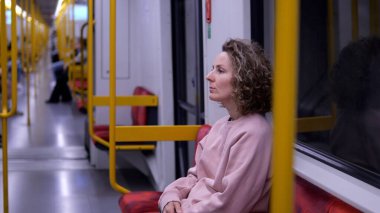 Metroda oturan genç bir kadın rutin yolculukta pencereden derin derin bakıyor. Düşünceli şehir sakinliği ve içsel durgunluk anında kayboluyor. Metroda günlük hareket