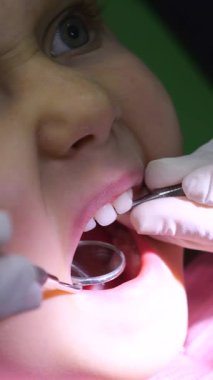 Dikey ekran, dişçi rutin kontroller sırasında genç kızların dişlerini dikkatlice inceliyor, klinik ortamlarda oral sağlık değerlendirmesi için profesyonel diş aletleri kullanıyor.