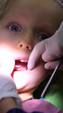 Dikey ekran, bir pediatrik dişçinin kapanışı genç bir kızın dişlerini inceleyen, diş aynası ve diğer aletler kullanan, rutin bir kontrol sırasında