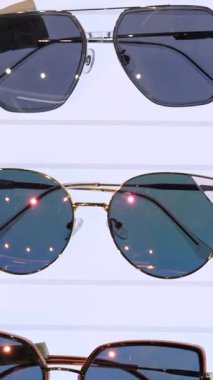 Dikey ekran, çeşitli şekillerde, renklerde ve boyutlarda şık güneş gözlükleri temiz beyaz bir arkaplanda sergilenerek moda ve göz koruma için çeşitli seçenekler sunulmaktadır.