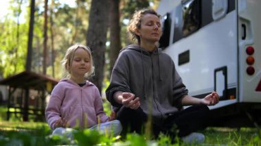 Kafkas anne ve kızı, karavanın yakınındaki huzurlu bir doğal ortamda yoga ve meditasyon yaparak aile bağlarını ve farkındalığı teşvik ediyorlar. Yoga konsepti ve çocuklarla meditasyon