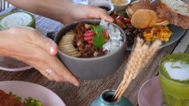 Tahta masaya yayılmış kahvaltı. İçinde canlı acai kasesi, granola, meyve ve çeşitli sabah yemeği bileşenleriyle birlikte matcha latte var.