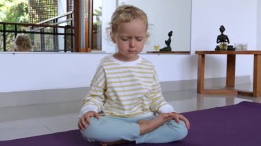 Genç pratisyen mor yoga minderinde bacak bacak üstüne atmış oturuyor. Sakin bir ifadeyle dikkatli meditasyon yapmaya çalışıyorum. Evde iç sakinlik ve konsantrasyon gelişiyor