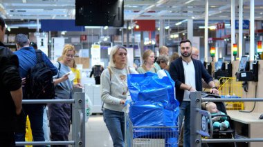 Varşova, Polonya - 01 Mayıs 2024: Mallarla dolu alışveriş arabaları olan müşteriler, bir perakende mağazasındaki işlek kasa kuyruğunda gezinerek alışveriş deneyiminin keyfini çıkarıyorlar
