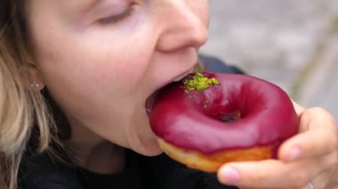 Şam fıstıklı nefis kırmızı kadife donut. Sokak anlarında büyüleyici genç bir kadın. Saf zevk ve coşkuyla tatlı hoşgörünün tadını çıkarıyor.