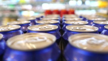 Çoklu mavi alüminyum kutular süpermarket rafında sergileniyor, kamera yaklaştıkça çerçeveyi yavaş yavaş dolduruyor, bolluk ve tüketici seçimi hissi yaratıyor
