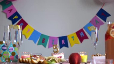 Renkli afişler, pasta, meyve, şampanya ve beşinci dönüm noktasını kutlayan parti unsurlarıyla süslenmiş doğum günü kutlaması.