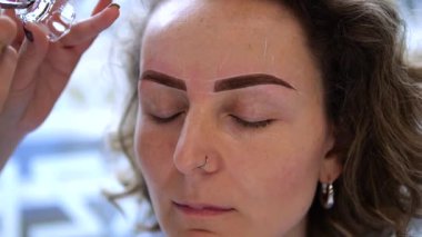 Profesyonel güzellik uzmanı titizlikle uzmanlaşmış kaş boyası uyguluyor, müşterilerin yüz hatlarını estetik tedavi ve uzman güzellik teknikleriyle değiştiriyor.