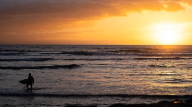 Gün batımlı sörfçü ve Endonezya, Bali sahilinde dalgalar