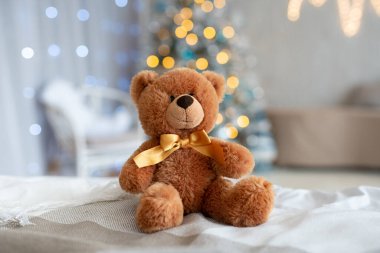 Süslü bir Noel ağacının önünde pelüş bir ayının olduğu samimi bir sahne. Tatil sezonu için mükemmel bir hediye. Ilık ve şenlikli bir neşe yayıyor, insan yok. Yeni yıl hediyesi