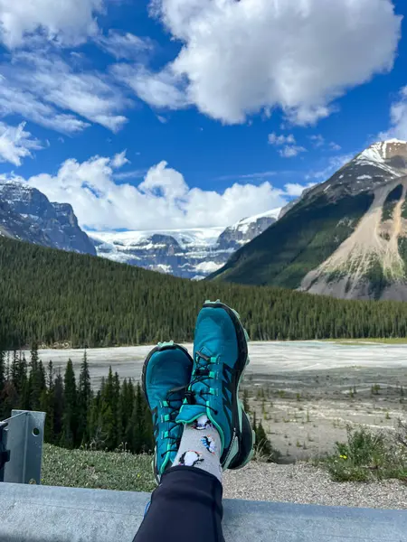 People with their feet up looking at the scenic view of the Athabasca River and surrounding mountains in Jasper National Park in Canada on a beautiful day.