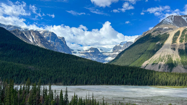 The scenic view of the Athabasca River and surrounding mountains in Jasper National Park in Canada on a beautiful day.