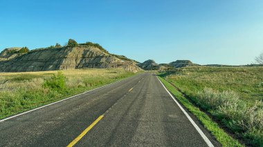 Güneşli bir günde Kuzey Dakota 'daki Theodore Roosevelt Ulusal Parkı' nda Çorak Topraklar tepelerinden ve dağlardan geçmek.