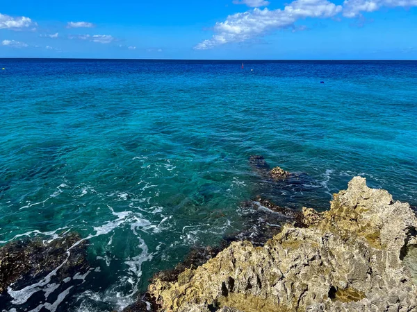 The clear turquoise blue ocean off of turtle reef in Cayman Islands on a beautiful blue sky day.