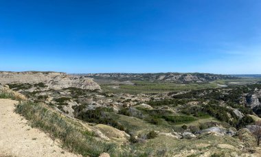 Güneşli bir günde, Kuzey Dakota 'daki Theodore Roosevelt Ulusal Parkı' ndaki Oxbow Overlook 'daki Çorak Topraklar tepeleri ve dağlar.