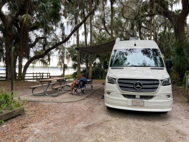 Dora Dağı, FL ABD - 13 Aralık 2022: Güneşli bir kış gününde Florida 'nın Dora Dağı' ndaki Trimble Park 'taki gölün kıyısında bir adam.